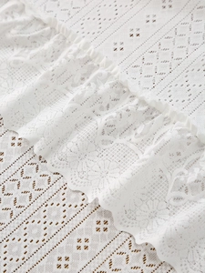 Macro shot of Nordic white lace tablecloth featuring delicate hollow floral patterns