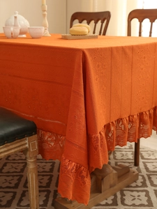 Detail of burnt orange lace tablecloth with openwork embroidery and crochet edges