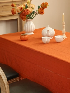 Detailed close-up of orange lace tablecloth with hollow embossed texture and knit edges