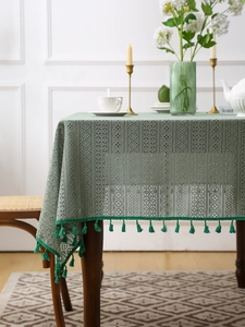 Dettaglio della tovaglia di pizzo verde con motivi traforati e bordi decorati con nappe
