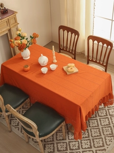 Detail of orange rectangular tablecloth with lace edges and floral jacquard texture