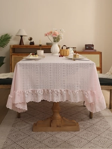 Detail of light pink lace tablecloth featuring intricate hollow patterns and pleated edges