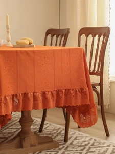 Close-up of orange vintage tablecloth with textured stripes and elegant lace borders