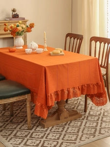 Detail of orange hollow lace tablecloth with elegant ruffled edges on wooden table