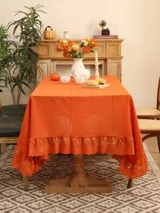 Detailed view of orange lace tablecloth featuring vertical jacquard texture and ruffled edges