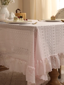 Detailed view of light pink lace tablecloth with geometric hollow patterns and ruffled edges
