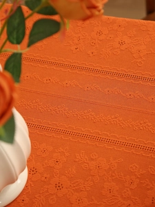 Macro detail of burnt orange lace tablecloth with vintage floral knit and hollow patterns