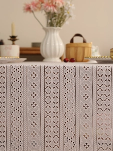 Close-up of cream white lace tablecloth featuring geometric hollow-out weaving and fringe