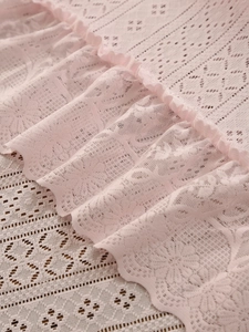 Detail of pink lace tablecloth with delicate floral embroidery and ruffled edges
