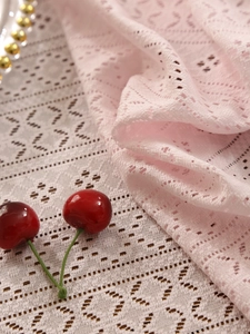 Detail of pink vintage lace fabric with delicate geometric openwork and soft texture