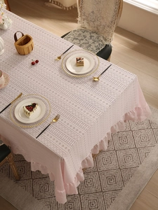 Close-up of light pink lace tablecloth featuring hollow geometric textures and ruffled edges