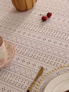 Detailed close-up of vintage beige crochet lace tablecloth with floral hollow-out patterns