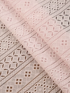 Detail of light pink lace tablecloth with delicate openwork weave and floral patterns