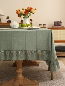 Close-up of sage green tablecloth featuring embossed texture and floral lace edging