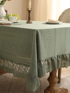 Macro detail of moss green lace tablecloth featuring floral scalloped edges and ribbed texture