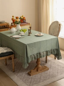 Close-up of sage green tablecloth with lace trim and hollow embroidery details