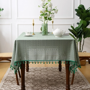 Tovaglia in pizzo traforato verde bosco con nappe decorative in un ambiente rustico