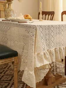 Close-up of cream white lace tablecloth with geometric hollow patterns and ruffled edges