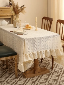 Detailed view of cream lace tablecloth with intricate hollow crochet and ruffled edges