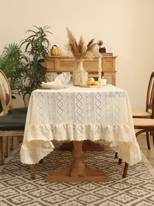 Detail of cream lace tablecloth with intricate floral patterns and elegant ruffled edges