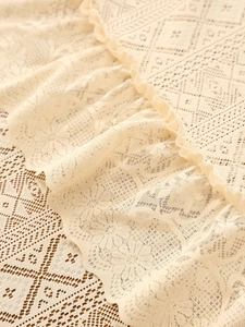 Macro view of beige lace tablecloth with hollow textures and ruffled edge details