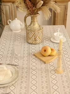 Detail of beige bohemian lace tablecloth with diamond crochet pattern on dining table