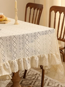 Close-up of beige vintage lace tablecloth with ruffled edges and diamond weave detail