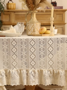 Detail of cream lace tablecloth with diamond weave pattern and floral scalloped edges