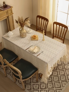 Close-up of cream lace tablecloth featuring geometric patterns and ruffled lace edges