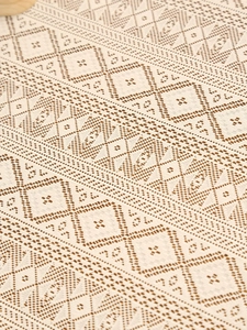 Macro view of Nordic style beige lace tablecloth with geometric mesh and wave patterns