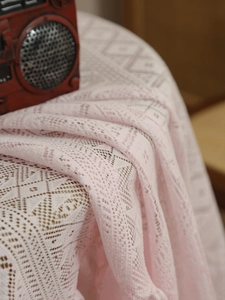 Close-up of pink hollow-out lace tablecloth with vintage radio home decor
