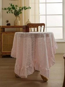 Close-up of pale pink lace tablecloth with elegant ruffled edges and hollow texture
