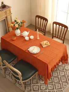 Macro detail of orange crochet tablecloth with hollow geometric patterns and ruffled edges