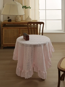 Detail of light pink lace tablecloth featuring intricate floral patterns and ruffled edges
