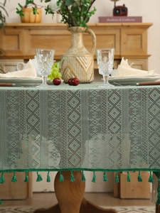 Detail of sage green crochet lace tablecloth with rhombic hollow patterns and handmade tassels
