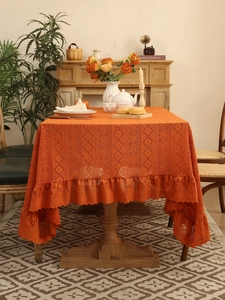 Detail view of orange crochet lace tablecloth featuring ruffled edges and hollow-out knit