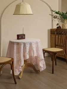 Close-up of vintage light pink lace tablecloth featuring ruffled edges and hollow diamond patterns