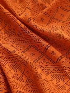 Detailed close-up of burnt orange lace tablecloth with hollow geometric crochet patterns