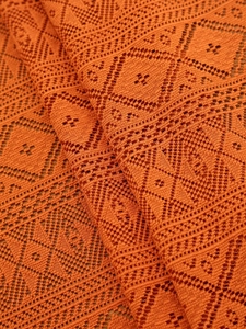 Close-up of burnt orange lace tablecloth showing intricate geometric hollow-out knit patterns