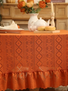 Detail of terracotta lace tablecloth with geometric mesh and elegant ruffled edge