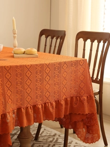 Detail of orange lace tablecloth showing intricate crochet patterns and ruffled edges