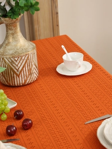 Close-up of bright orange hollow lace tablecloth with geometric knit pattern and texture
