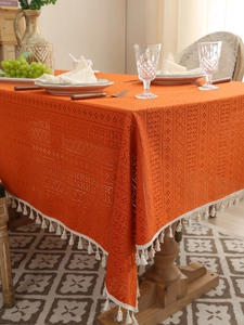 Close-up of orange lace tablecloth with crochet hollow patterns and white fringe edge