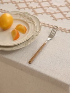 Close-up of beige linen tablecloth with geometric embroidery and thick texture