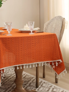 Detail of orange crochet lace tablecloth with white tassels for rustic home decor