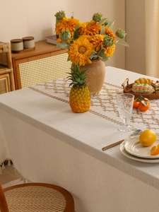 Close-up of linen tablecloth with geometric embroidery and tassel edges in warm natural light