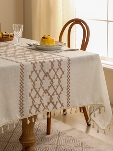 Close-up of oatmeal linen tablecloth with dark coffee diamond embroidery and fringe