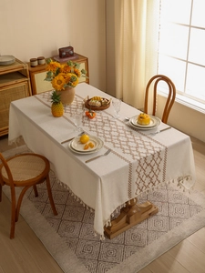 Close-up of cream linen tablecloth with brown geometric embroidery and elegant tassels