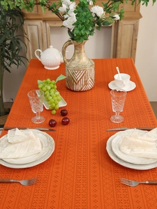 Detail of orange hollow lace tablecloth with intricate geometric crochet texture on a table