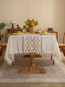 Close-up of linen tablecloth with brown diamond embroidery and fringe tassels